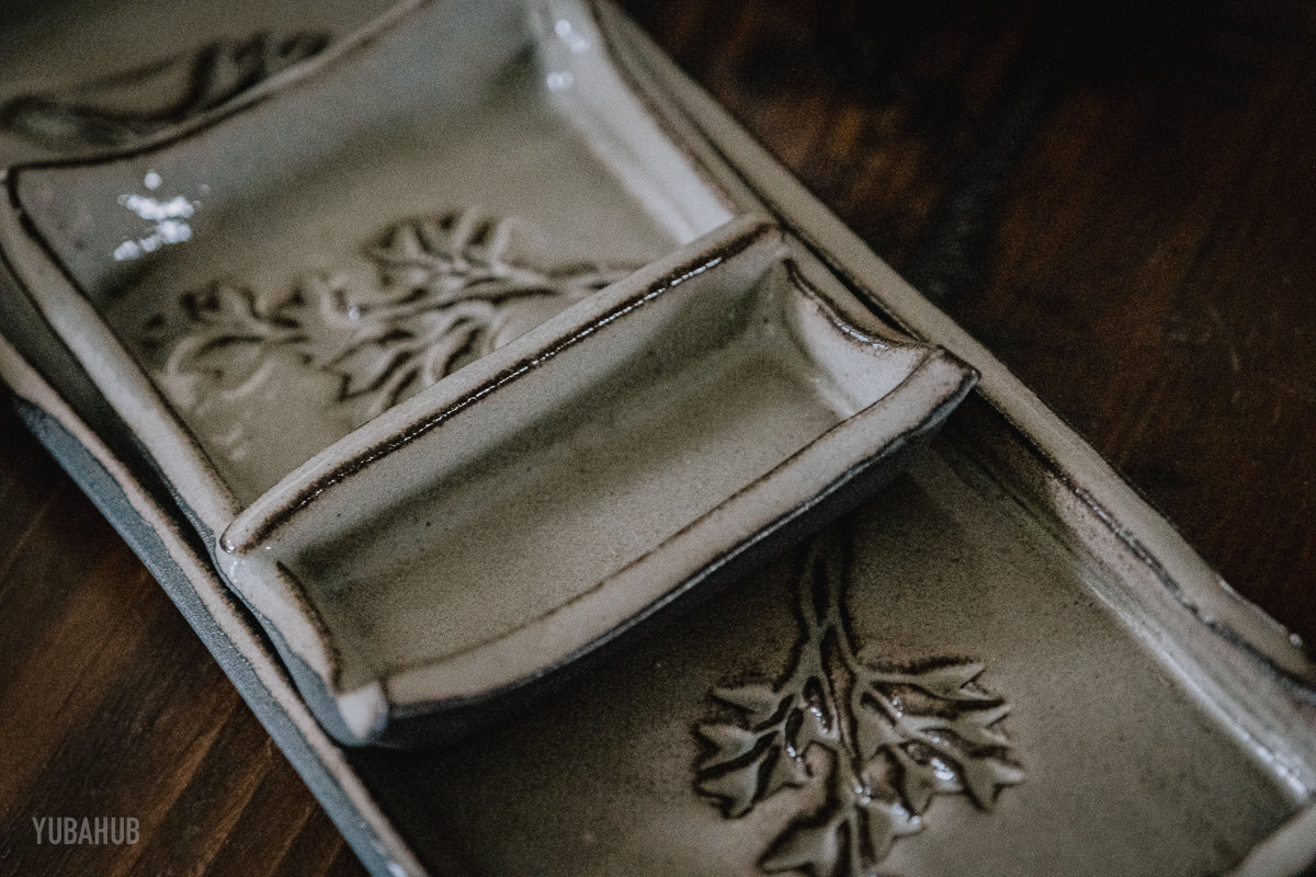 Cropped close up photo of a black ceramic sushi set with white glaze
