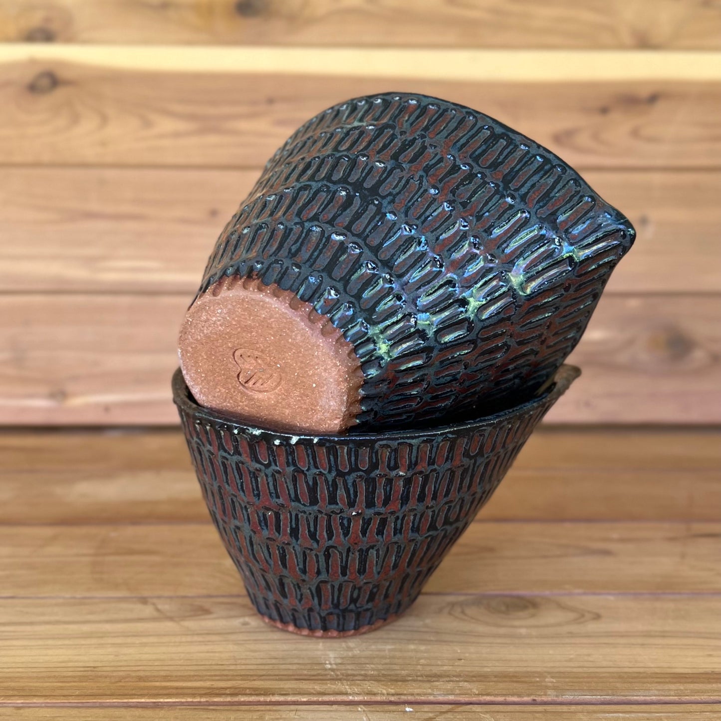 little ceramic carved espresso cup sitting askew on top of another cup against a wood background