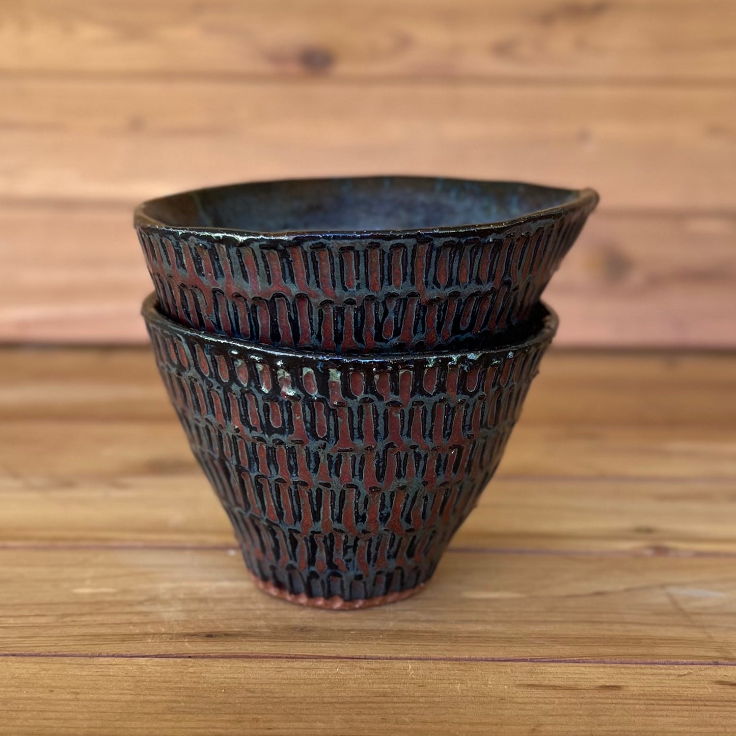 stack of two little ceramic carved espresso cups against a wood background