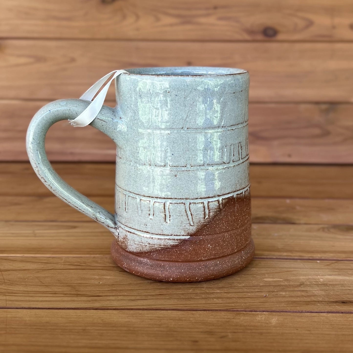 One carved red stoneware ceramic coffee mug with a blue grey glaze