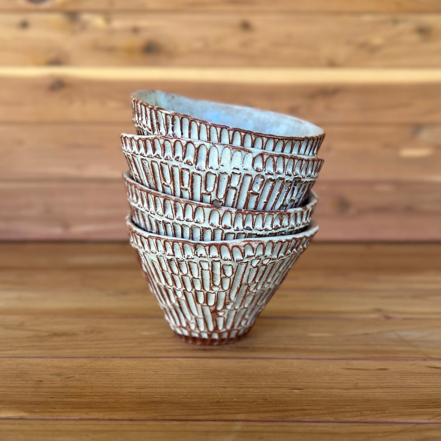 Stack of small carved red pottery tumblers with white glaze