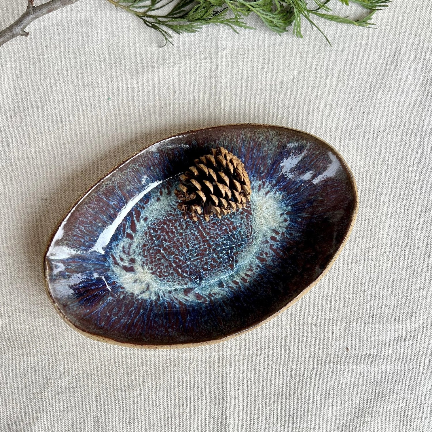 Large blue ceramic serving dish with speckled clay with a pinecone