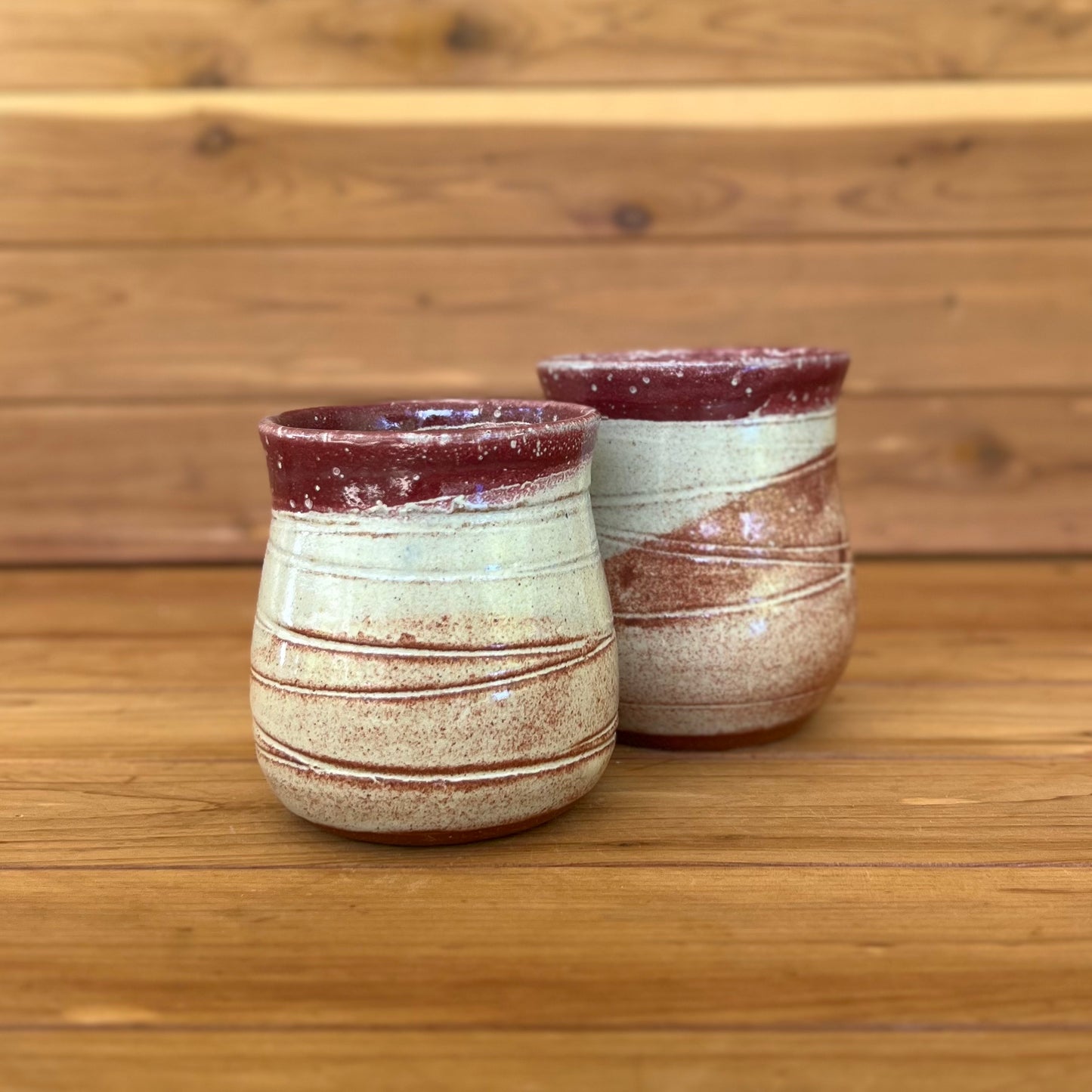 two small stemless red clay ceramic bell-shaped wine tumblers