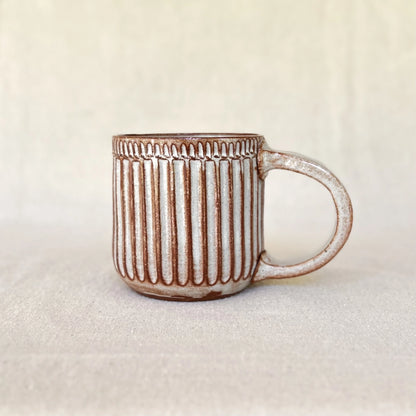 One red stoneware carved coffee mug with handle and white glaze
