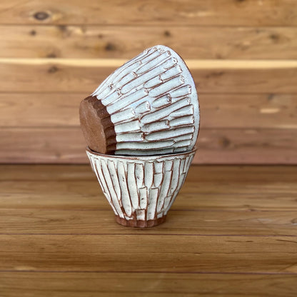 image of two small hand carved red clay espresso cups against a wood background