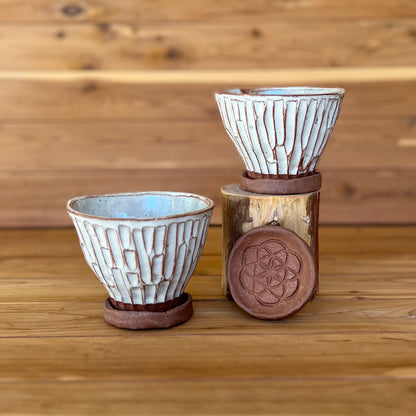 image of two small hand carved red clay espresso cups against a wood background