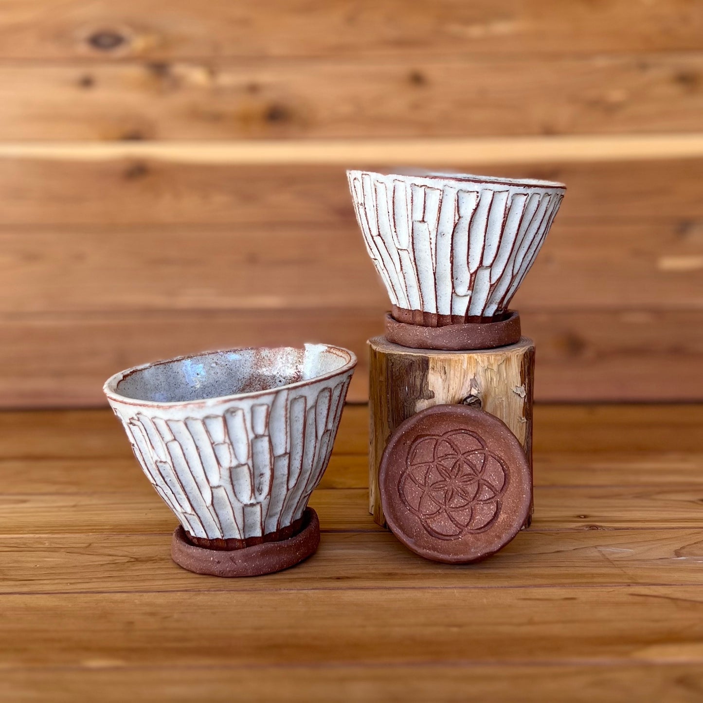 image of two small hand carved red clay espresso cups against a wood background