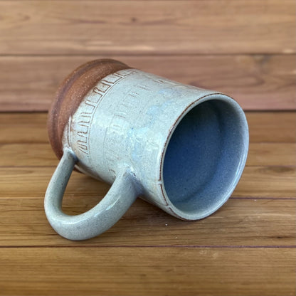 One carved red stoneware ceramic coffee mug with a blue grey glaze