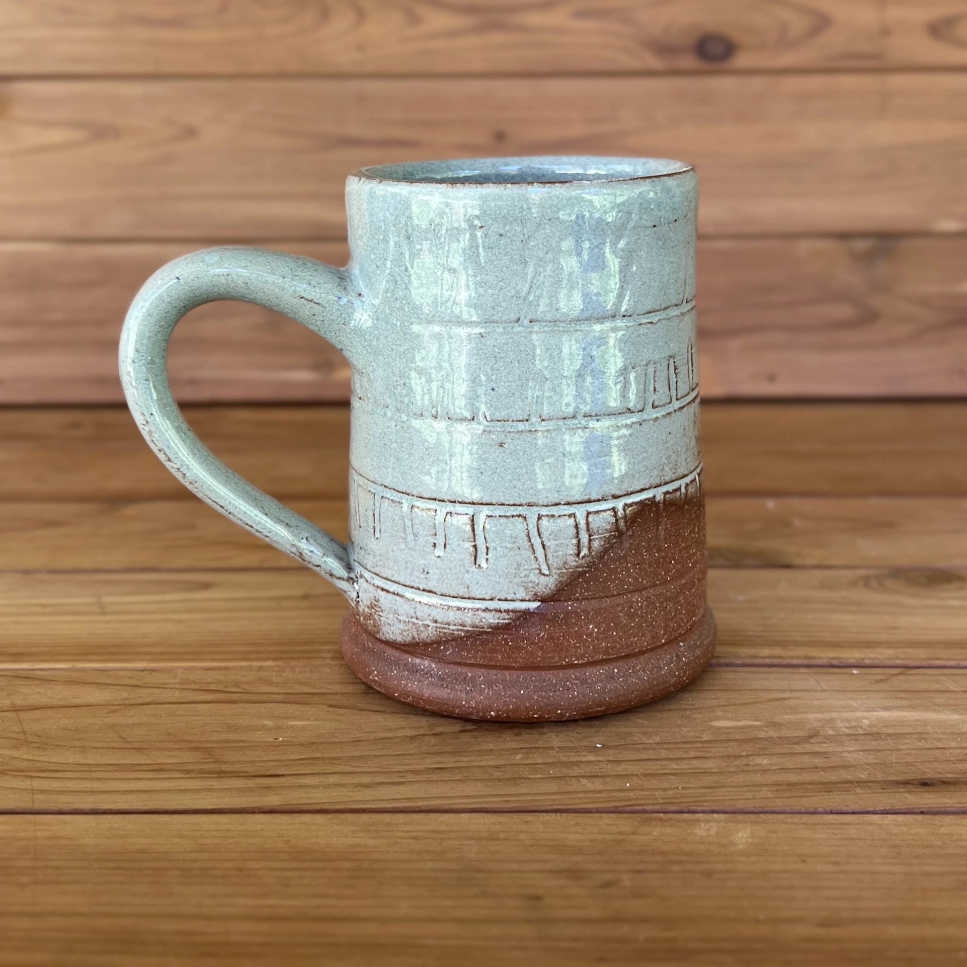 One carved red stoneware ceramic coffee mug with a blue grey glaze