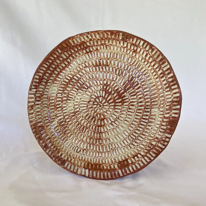 image of one large intricate hand carved red clay plate in front of a white background