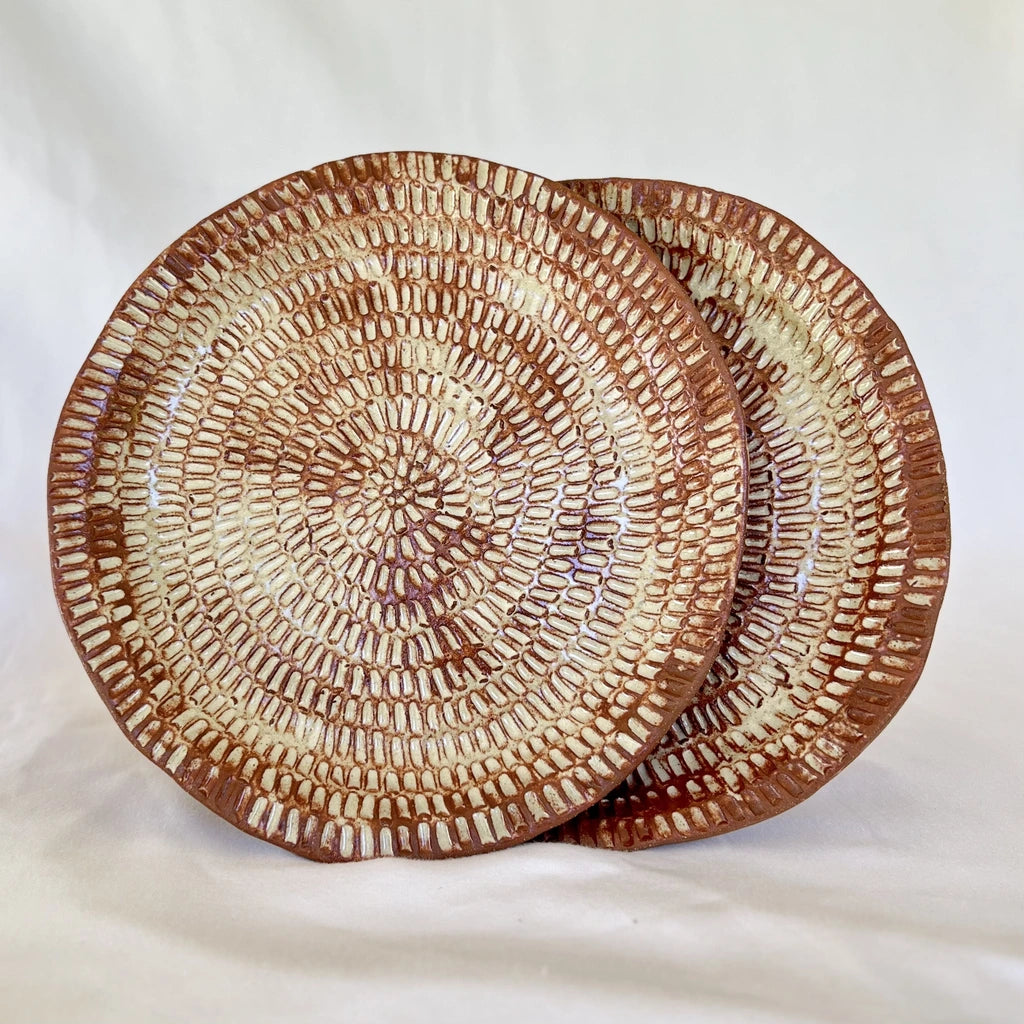 two red ceramic plates carved with cream glaze