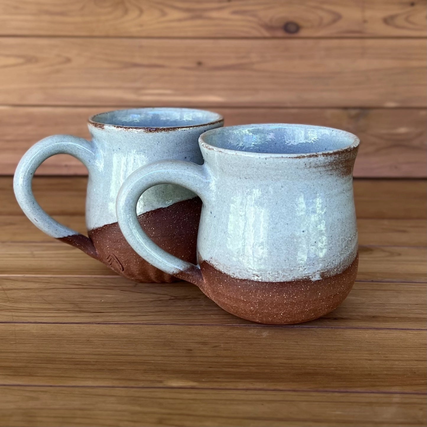 Pair of red stoneware pottery mugs glazed in blue