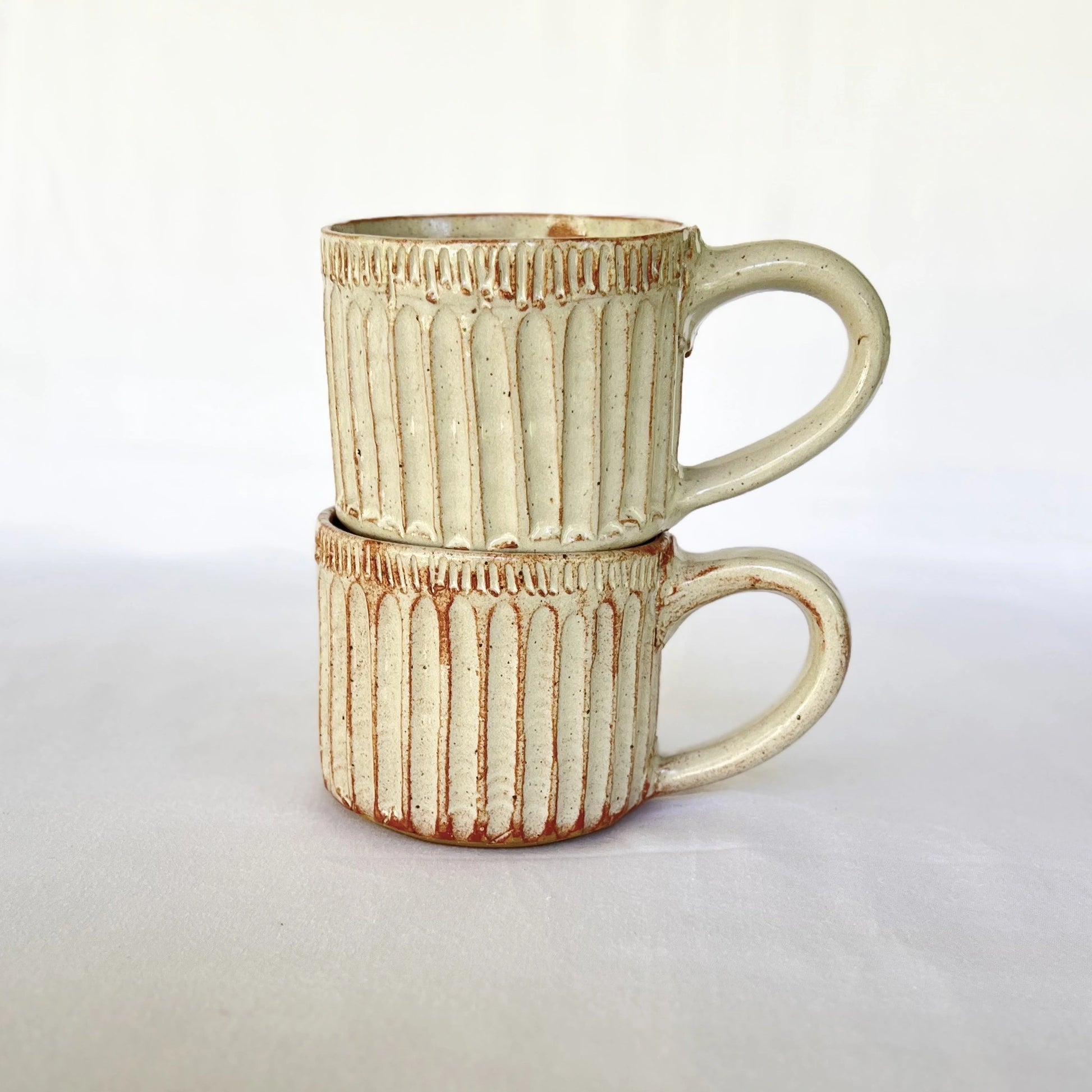 Stack of rustic white speckled ceramic cappuccino mugs with handles