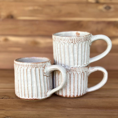 Three white carved speckled clay cappuccino mugs